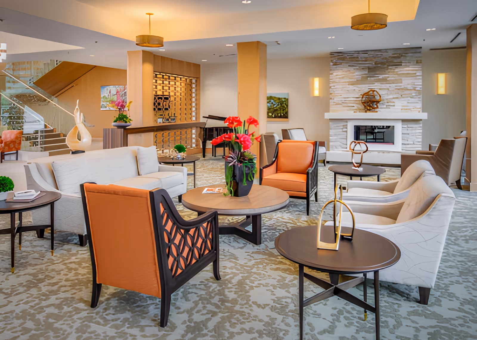 Spacious, well-lit communal lounge with sofas and armchairs arranged around coffee tables and a fireplace.