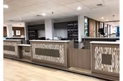 Interior lobby/reception area with a long wood-paneled front desk and shelving behind.
