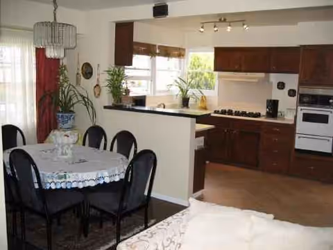 Open-plan dining area with a round table, black chairs, and adjacent kitchen.