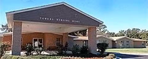Front view of Towers Nursing Home entrance with drive and landscaping.