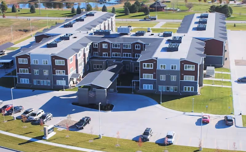 Aerial view from above of a Broadwell Senior Living building complex with parking and landscaped grounds.
