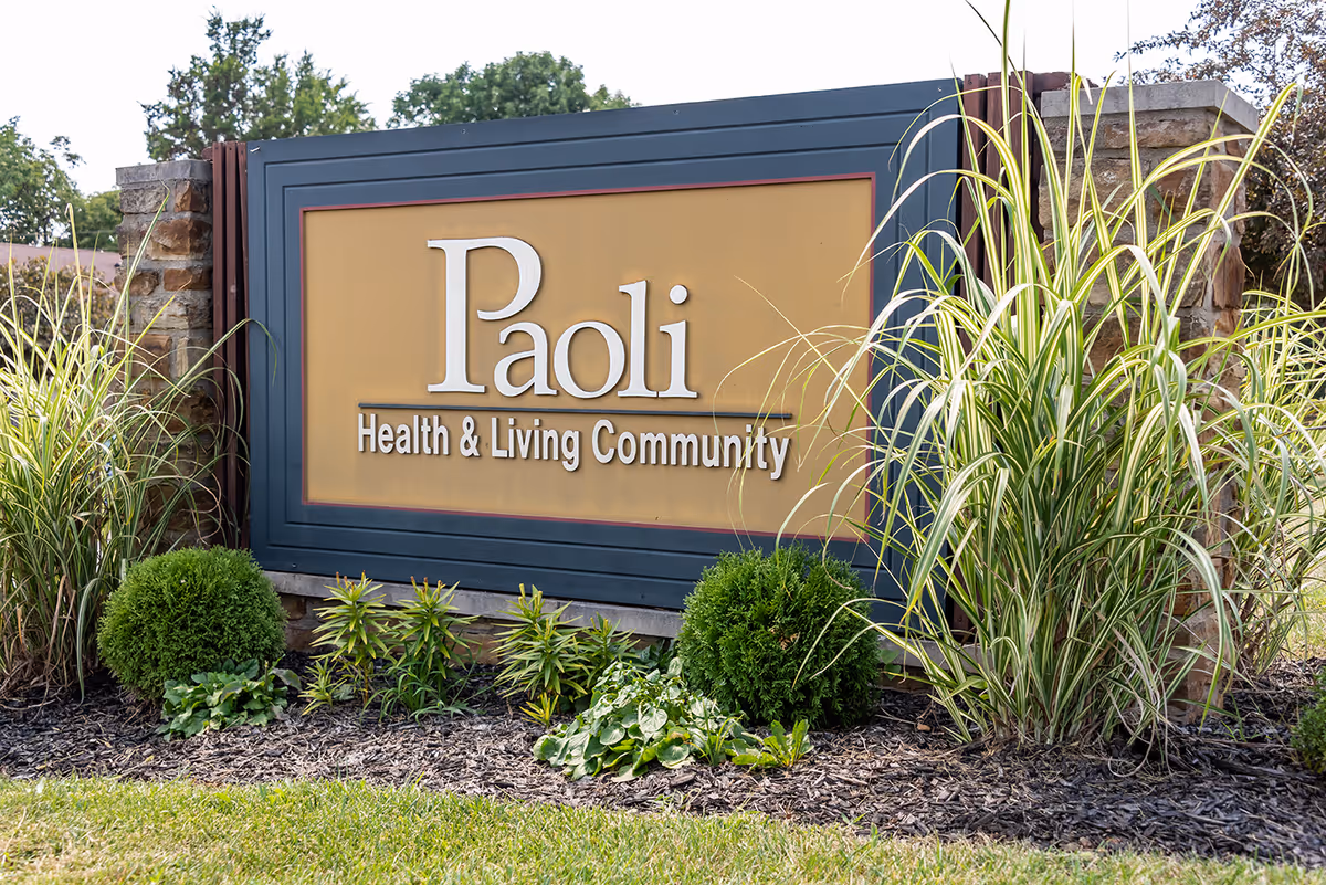 Outdoor entrance sign reading Paoli Health & Living Community surrounded by landscaping.