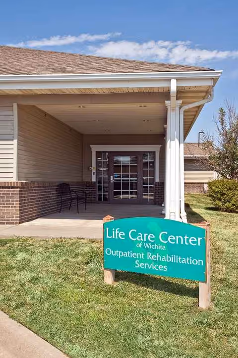 Front view of Life Care Center of Wichita entrance with a green sign and covered doorway.