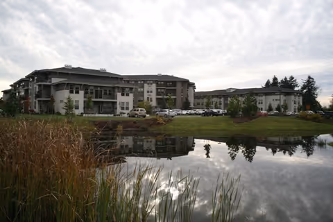 Exterior view of Spring Creek by Bonaventure showing a multi-building facility reflected in a pond.