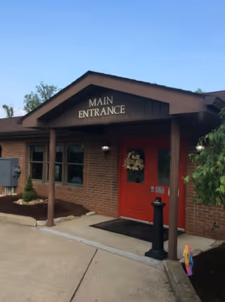 Brick building entrance with a red door under a porch labeled "Main Entrance".