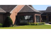 Exterior view of a brick nursing facility with glass entrance and manicured lawn.