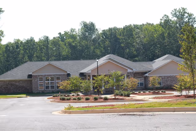 Exterior view of The Gardenias senior living facility with a landscaped front and parking.