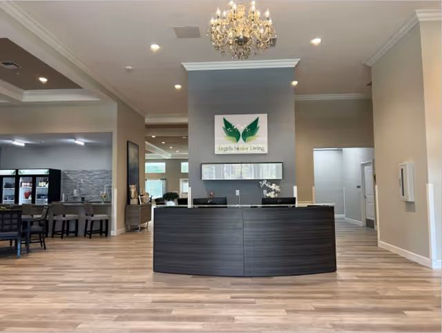 Reception desk in a senior living facility lobby with a chandelier and an 'Angels Senior Living' sign above.