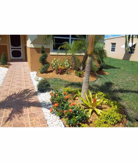A walkway with garden landscaping beside a beige senior living facility exterior.