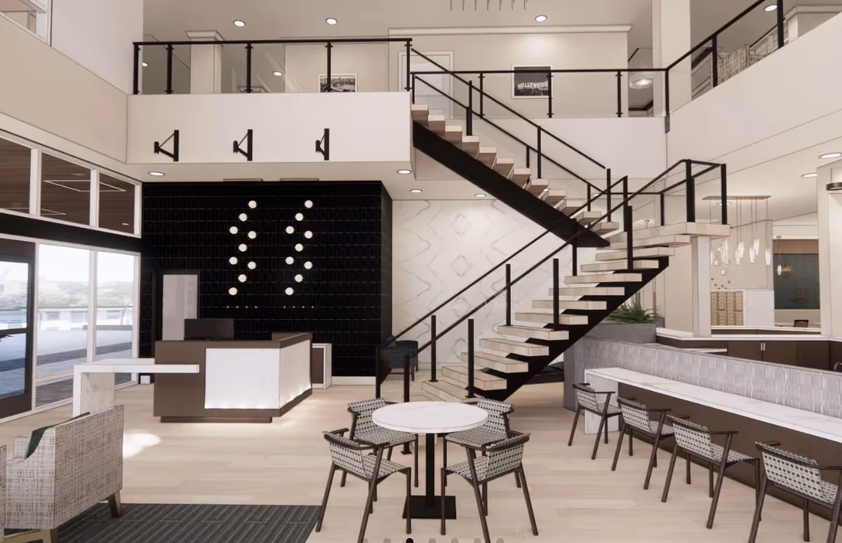 Spacious modern two-story senior living lobby with a central staircase, reception desk, and seating and dining areas.