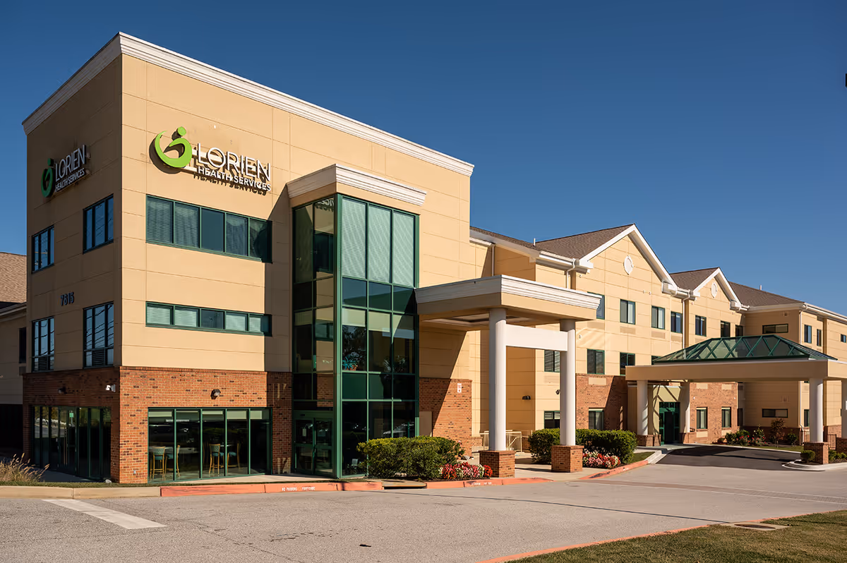 Exterior view of Lorien Elkridge senior living building with glass entrance and signage.