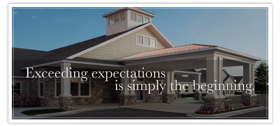 Exterior view of a senior living facility building with a covered entrance supported by stone pillars, under a clear blue sky.