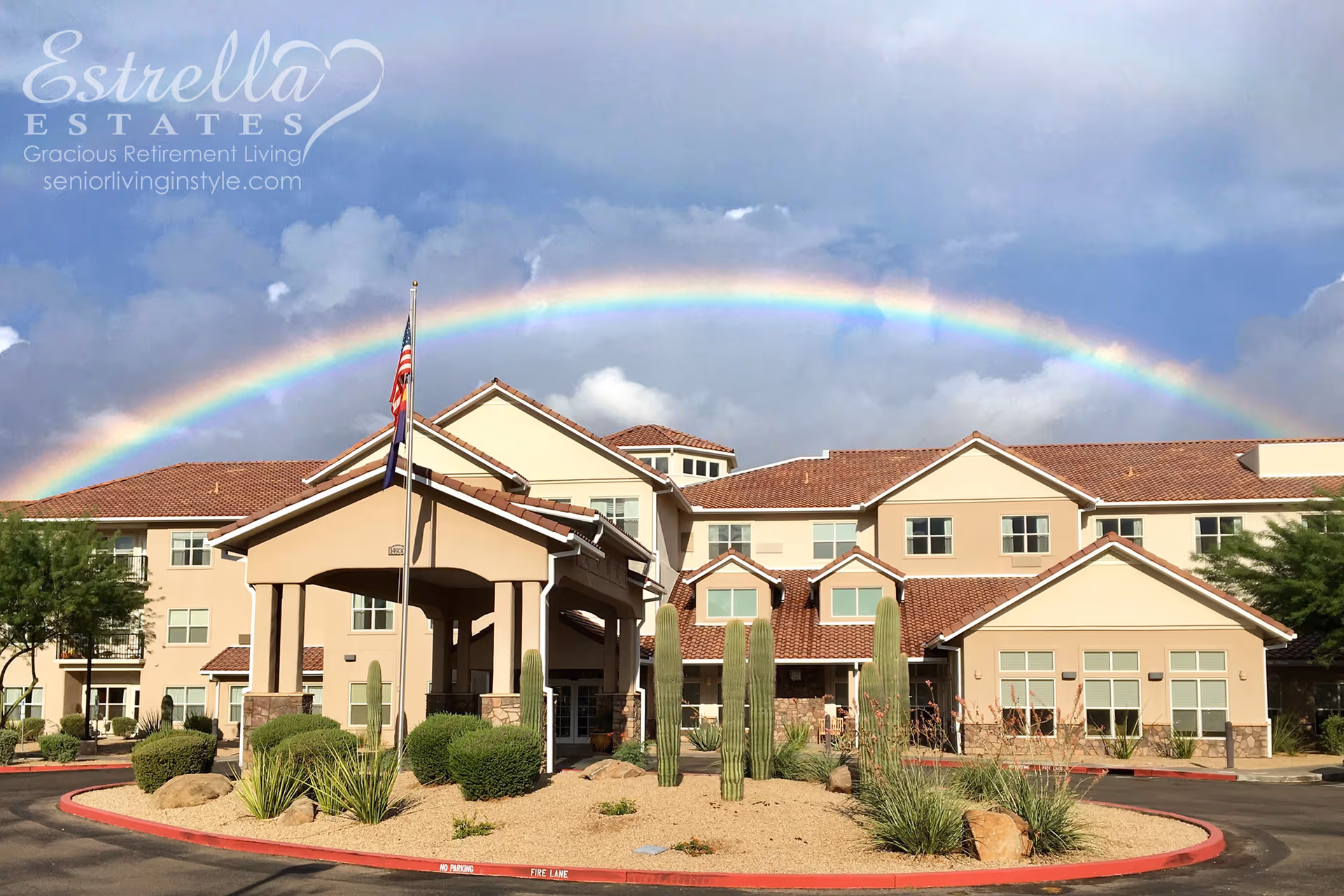 Front entrance of Estrella Estates retirement community with a rainbow arching overhead.