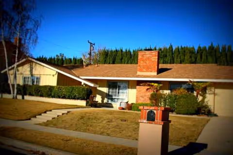 Exterior view of a single-story senior living building with a brick chimney and front yard.