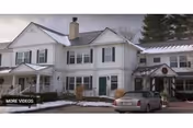 White Woodcrest Village Assisted Living exterior with snow, two-story building, and parked car.