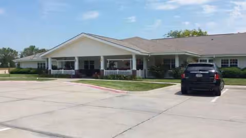 Single-story senior living facility with a covered front entrance and parked car.