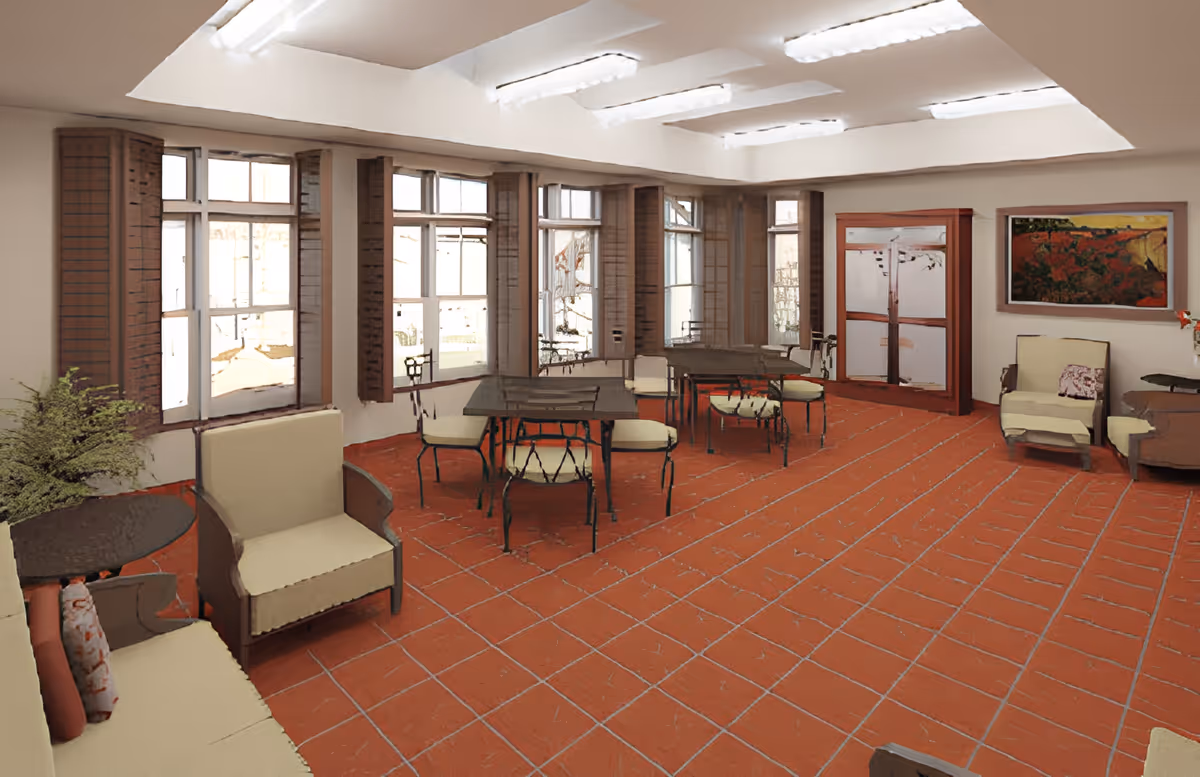 A spacious room with terracotta tiled flooring, multiple windows with wooden shutters, and several seating areas including cushioned armchairs and tables with chairs. The room is well-lit with ceiling lights and features a large painting on one wall and a wooden cabinet.