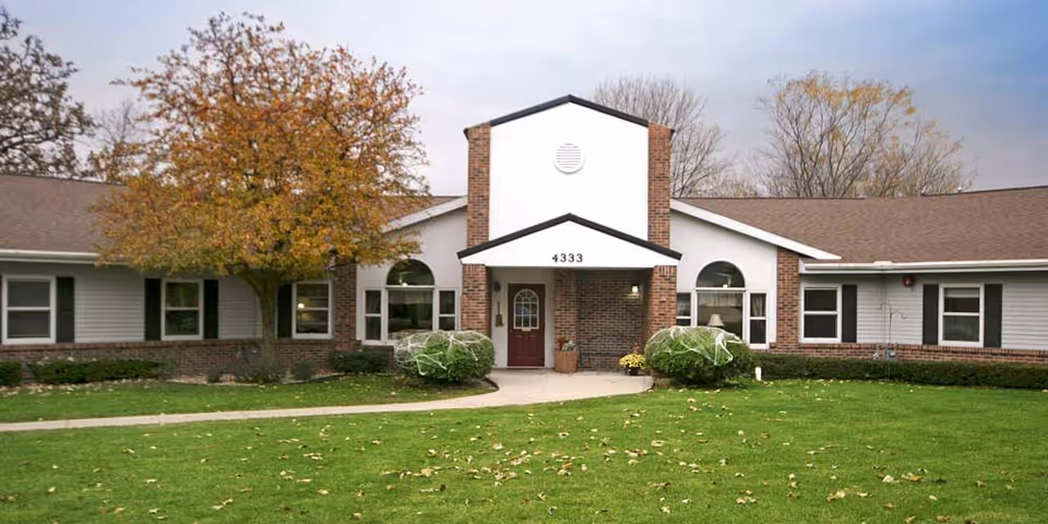 Front view of a single-story senior living facility with brick accents and a manicured lawn.