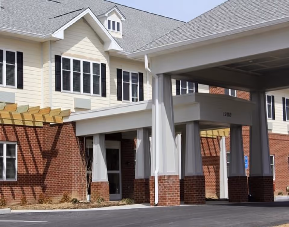 Covered entryway and porte-cochère of a two-story brick-and-siding senior living building.