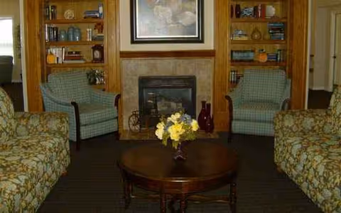 A cozy living room with a central coffee table, fireplace, and built-in bookshelves.