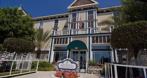 Exterior view of a multi-story senior living building with a green entrance canopy and landscaped front walkway.