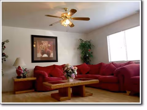 Red sectional sofa, wooden coffee table, plants, and artwork in a bright living room.