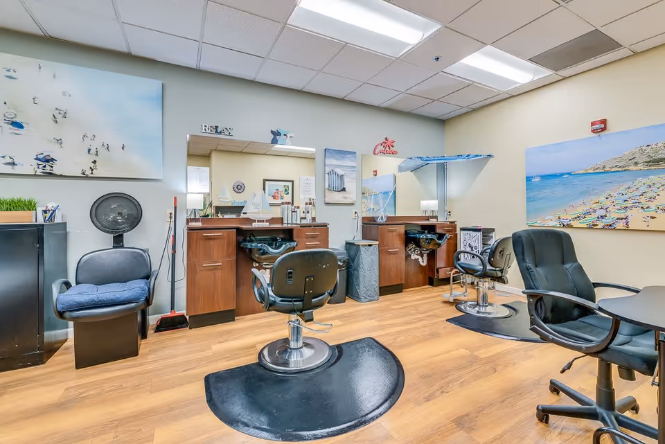 Interior hair salon with styling chairs, wash sinks, mirrors, and beach-themed wall art.