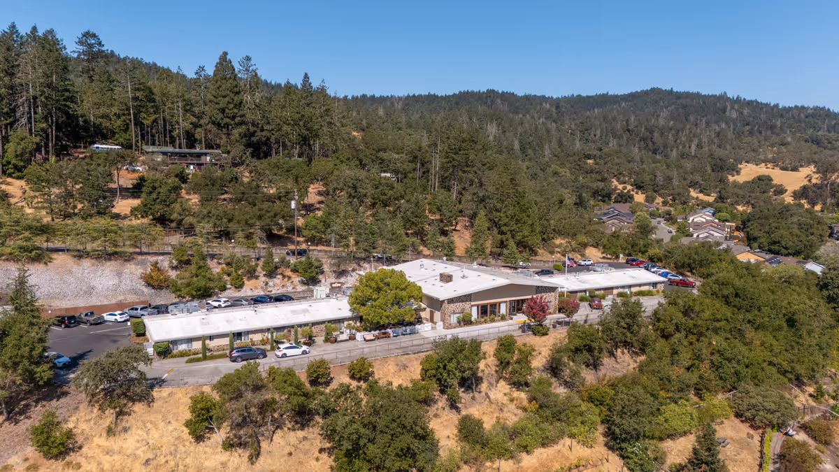 Aerial view of Cloverdale Healthcare Center single-story buildings and parking lot surrounded by trees and hills.
