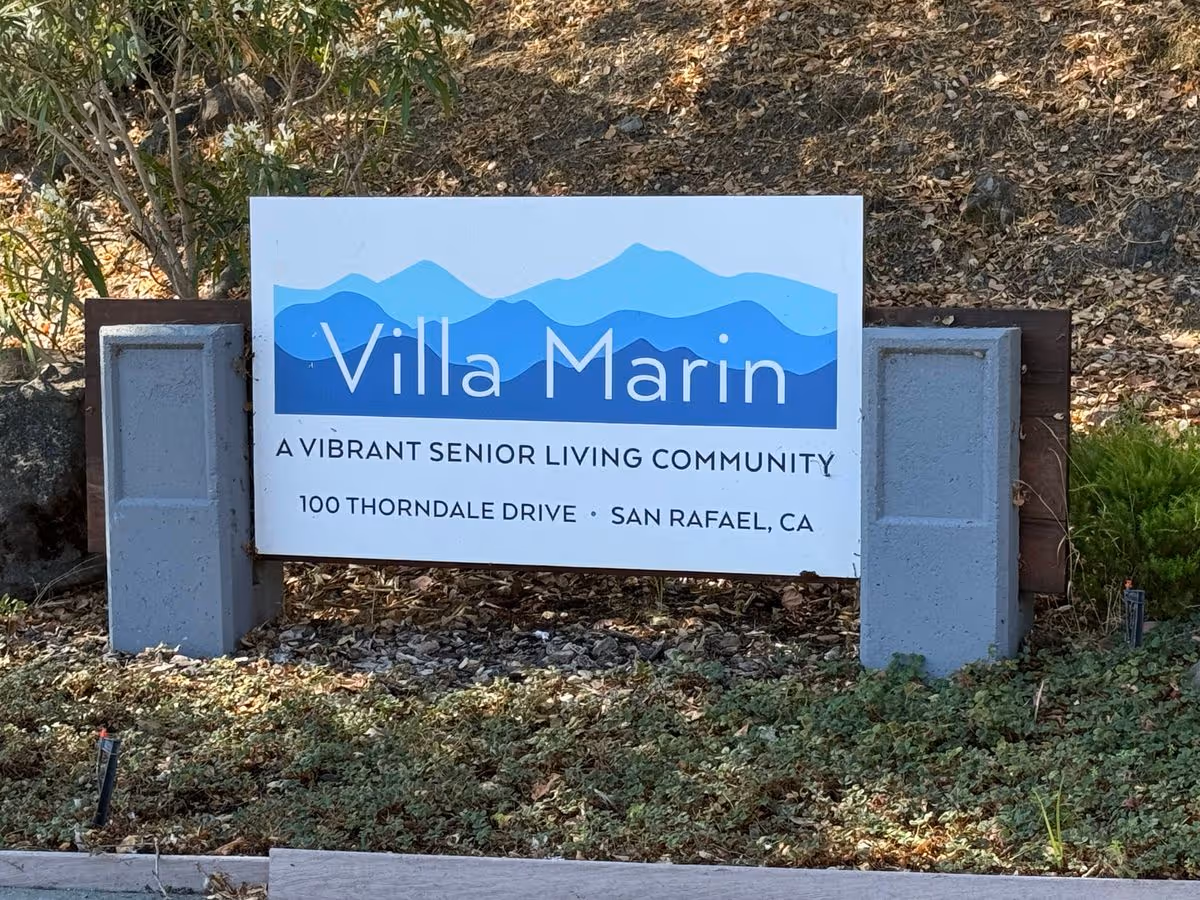 A freestanding outdoor sign reading "Villa Marin" for a senior living community with its address, set among landscaping.
