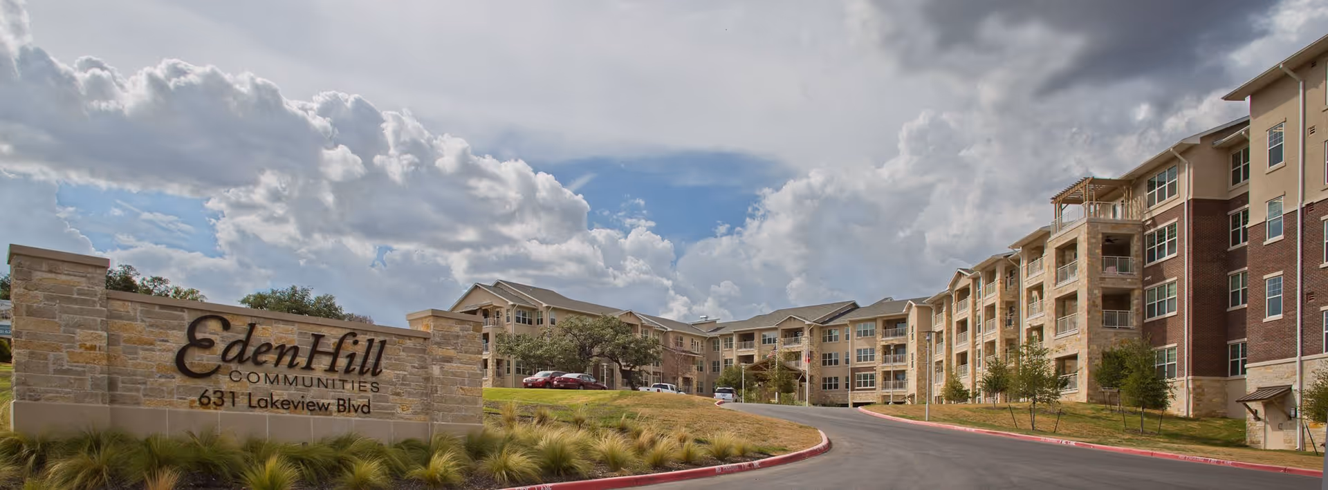 Front exterior of EdenHill Communities showing a stone entrance sign and a multi-story residential building under a cloudy sky.