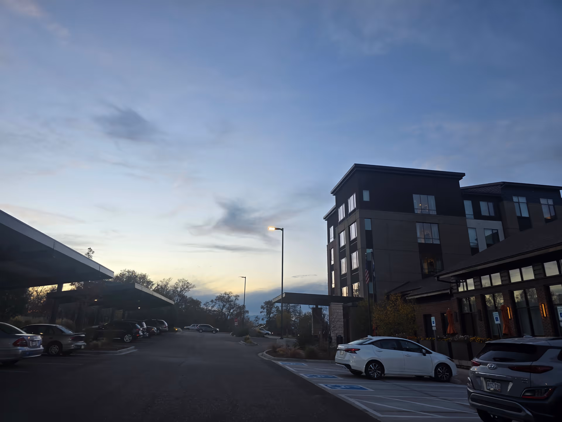 Exterior view of a multi-story senior living building and adjacent parking lot at dusk.