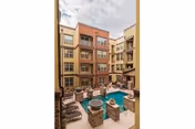 Courtyard of a multi-story senior living building with a central pool, hot tubs, lounge chairs, and surrounding balconies.