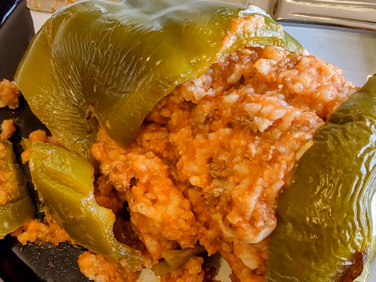 Close-up of a stuffed green bell pepper filled with a mixture of rice, ground meat, and tomato sauce on a plate.