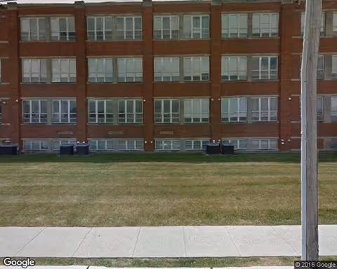 Exterior view of a red brick senior living building with lawn and sidewalk.