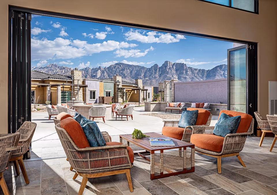 Open-air courtyard with wicker lounge chairs and a coffee table opening to a patio and mountain views.