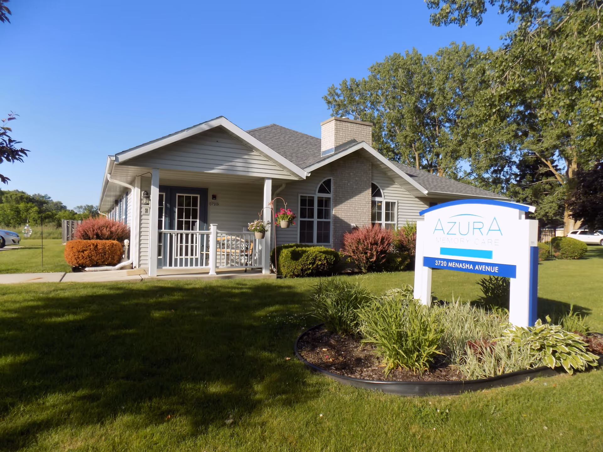 Front exterior of a single-story memory care building with a lawn and an 'Azura Memory Care' sign.