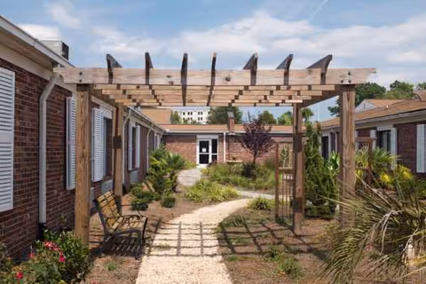 Outdoor courtyard of White Oak Manor Charleston with a wooden pergola and gravel path