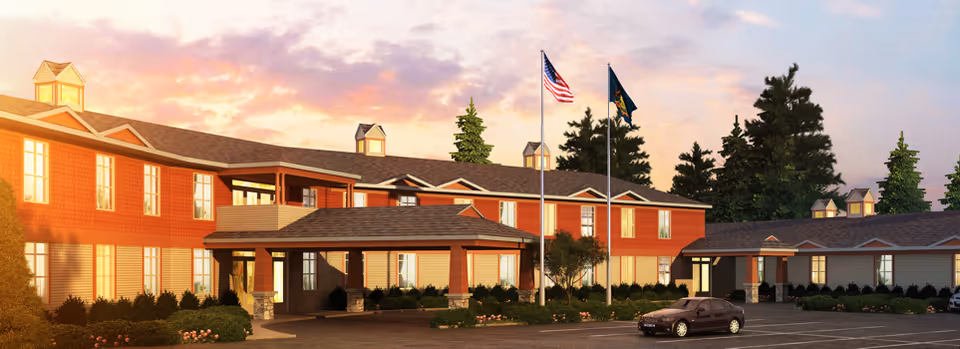 Exterior view of The Pines Senior Living building with flags, entryway, and landscaping