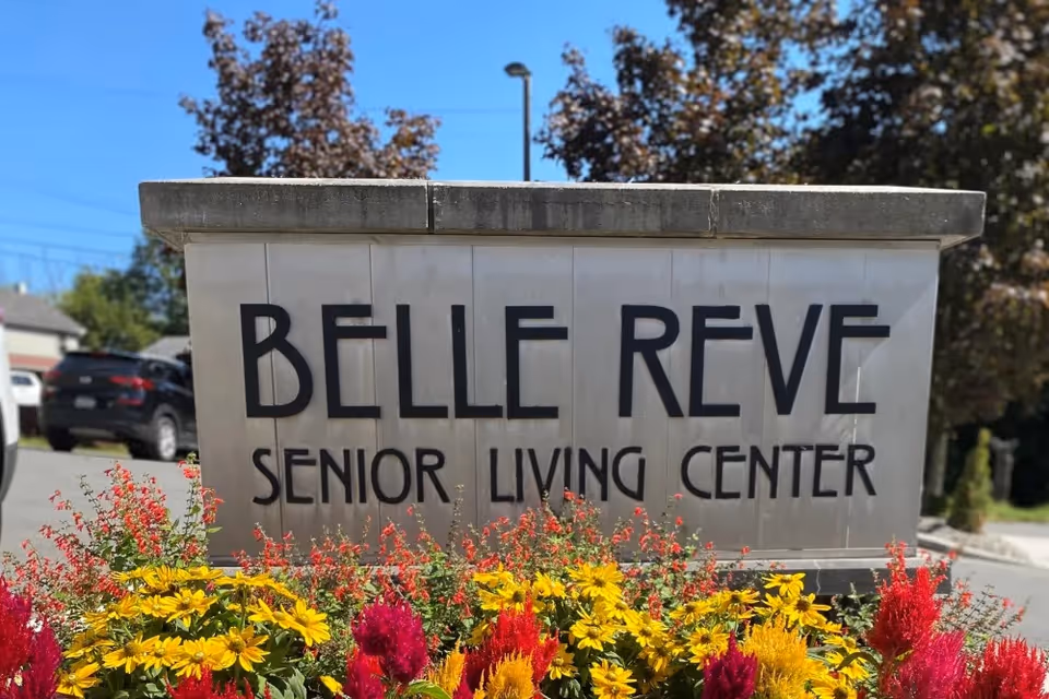 Stone sign that reads "BELLE REVE SENIOR LIVING CENTER" with colorful flowers in front.
