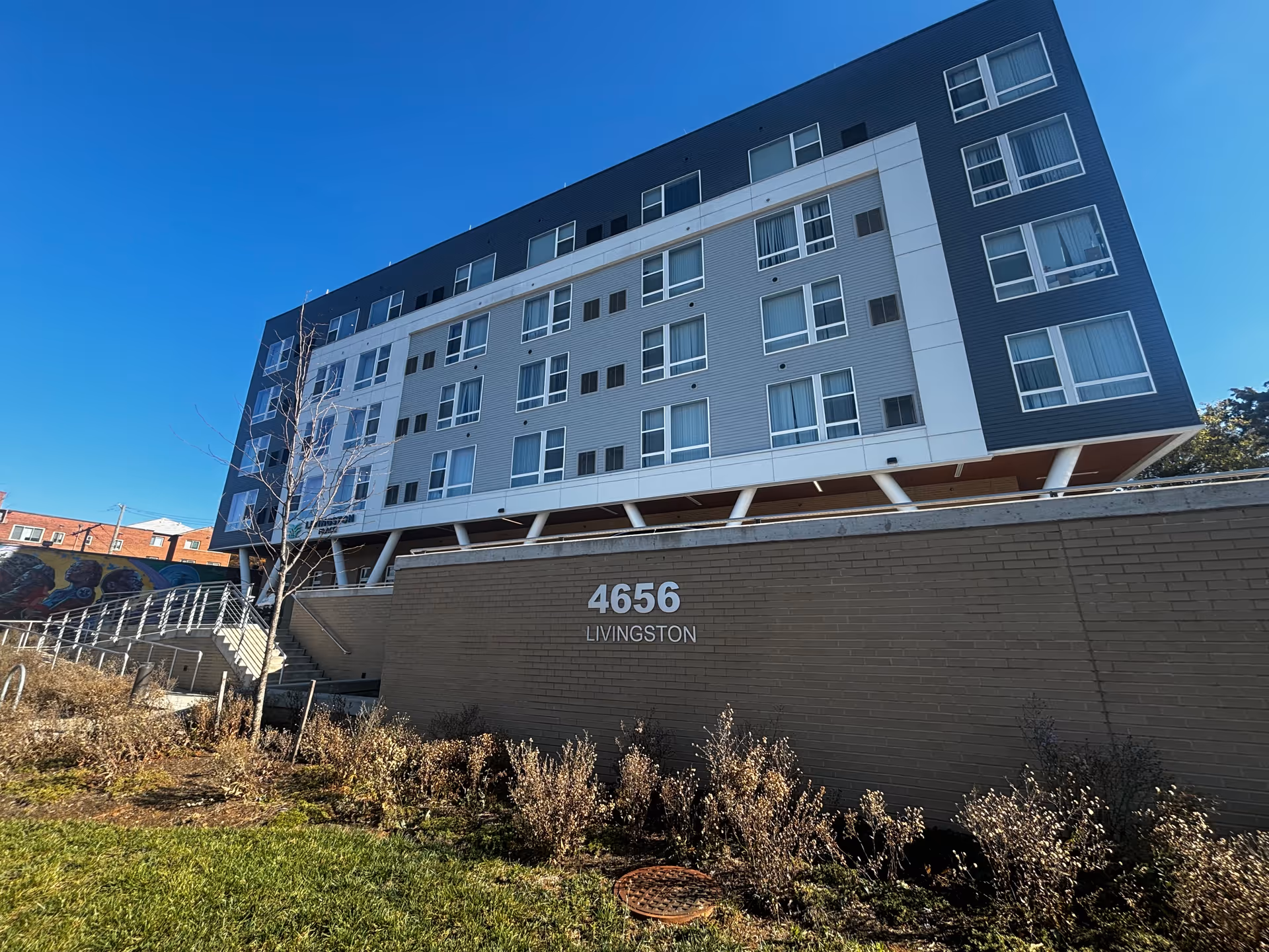 Front exterior of a modern multi-story building with '4656 LIVINGSTON' displayed on a brick wall.