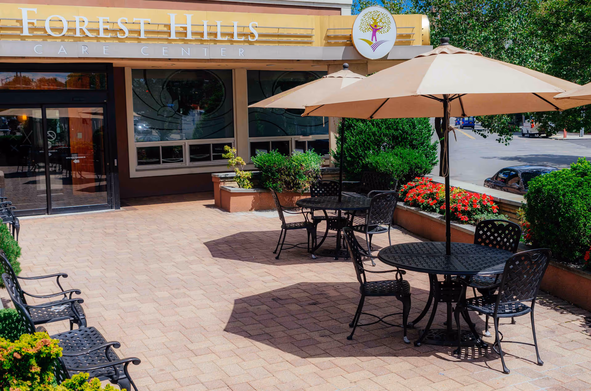 Patio seating with umbrellas, tables and chairs outside the Forest Hills Care Center entrance.