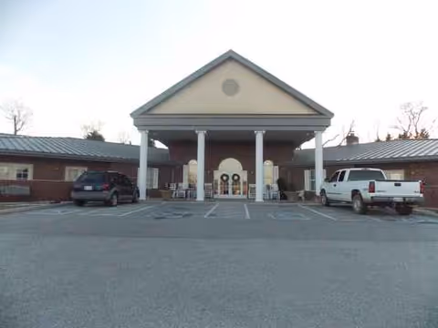 The front entrance of Trousdale Senior Living Center, brick building with a parking lot.