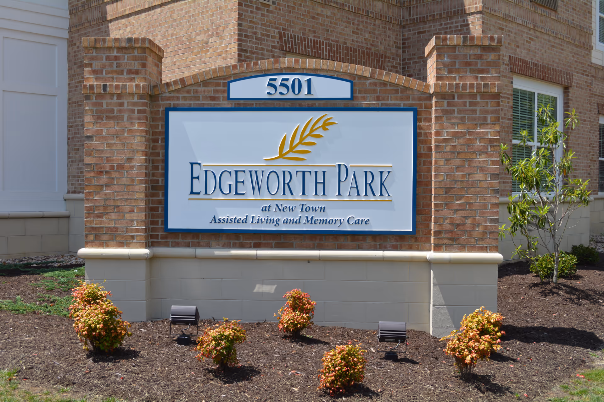 A brick building exterior with a large Edgeworth Park at New Town sign and landscaped shrubs in front.