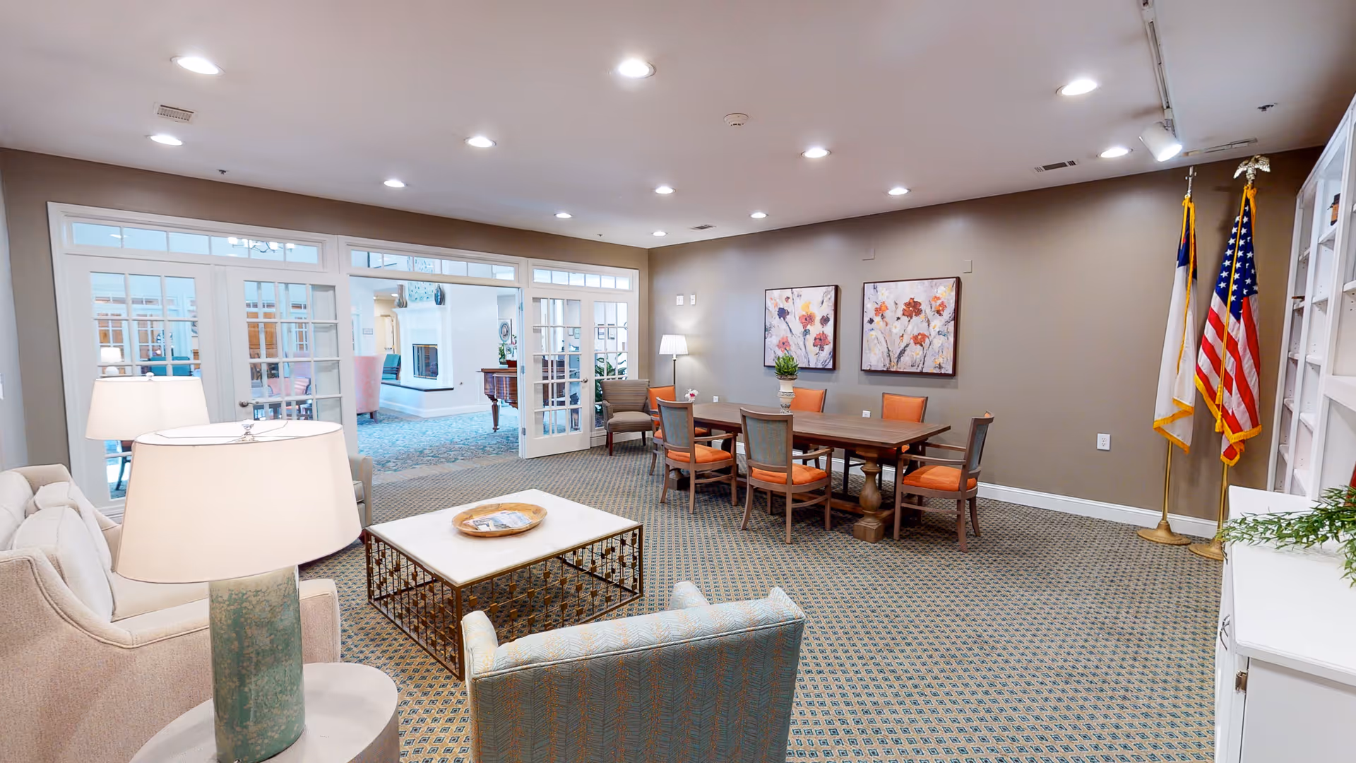 Communal lounge with sofas, a coffee table, a wooden table and chairs, wall art, and flags.