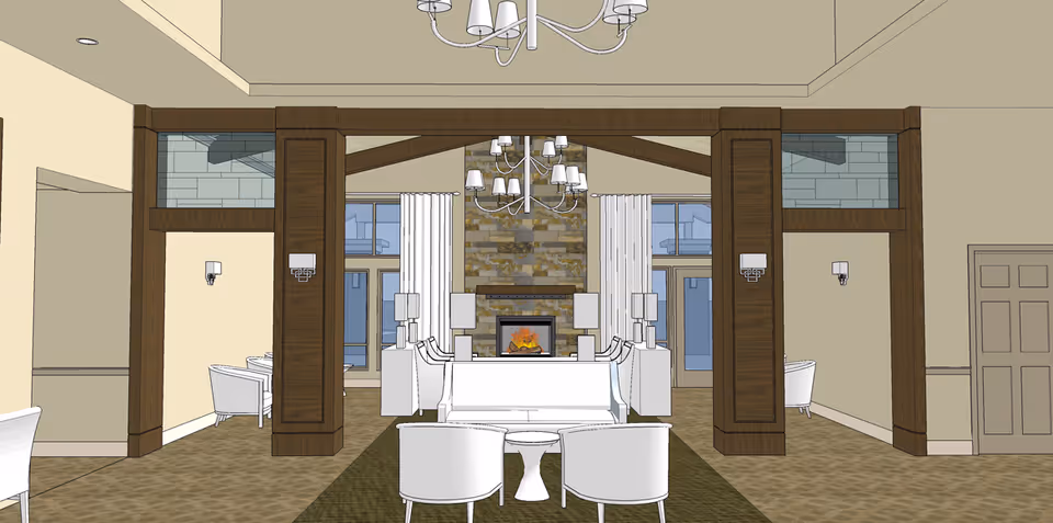 Interior view of a spacious living room area with a central fireplace made of stone, flanked by tall windows with white curtains. The room features white chairs and sofas arranged around the fireplace, wooden beams and columns, beige walls, and a chandelier hanging from the ceiling.