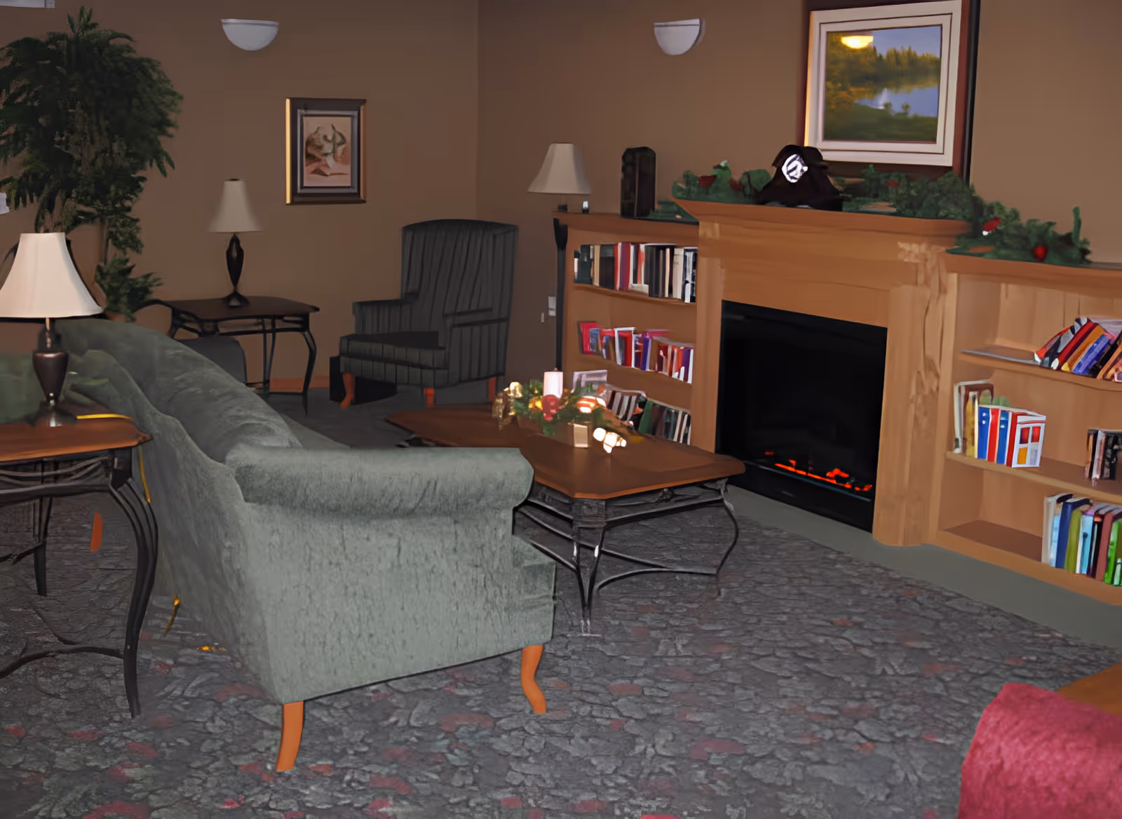 A cozy living room with a green sofa, a striped armchair, two side tables with lamps, a wooden coffee table decorated with candles and a centerpiece, a fireplace with a wooden mantel decorated with greenery and a framed landscape painting above it, and built-in bookshelves filled with books on either side of the fireplace.