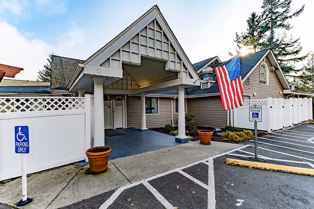Front entrance of Brookdale Harbor Bay with a covered portico, American flag, and handicap parking spaces.