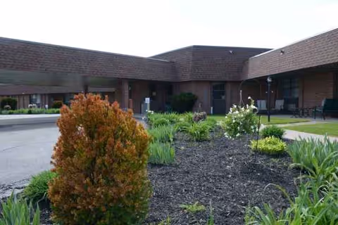 Exterior view of a brick senior living center with landscaped front garden and entrance.