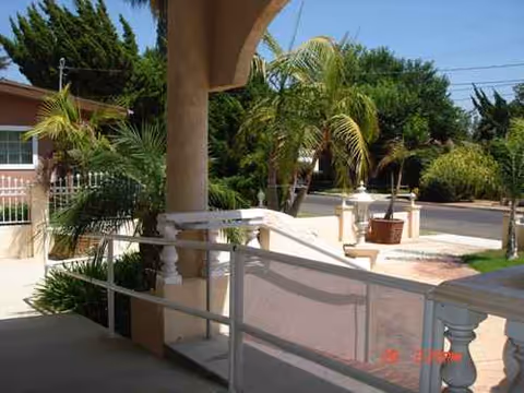 Exterior view of Peppertree Guest Home II showing a covered entrance, ramp, and palm trees.