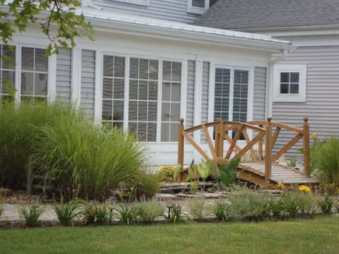 Exterior view of Monmouth ALF with a wooden footbridge over a landscaped garden.